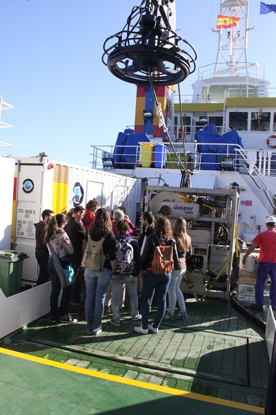 Los estudiantes de la UCA entretenidos admirando el ROV LIROPUS 2000 instalado en la popa del B/O Ramón Margalef. El Jefe de Campaña les explica las utilidades que tiene trabajar con un instrumental tan moderno como el Liropus 2000 y los componentes que t